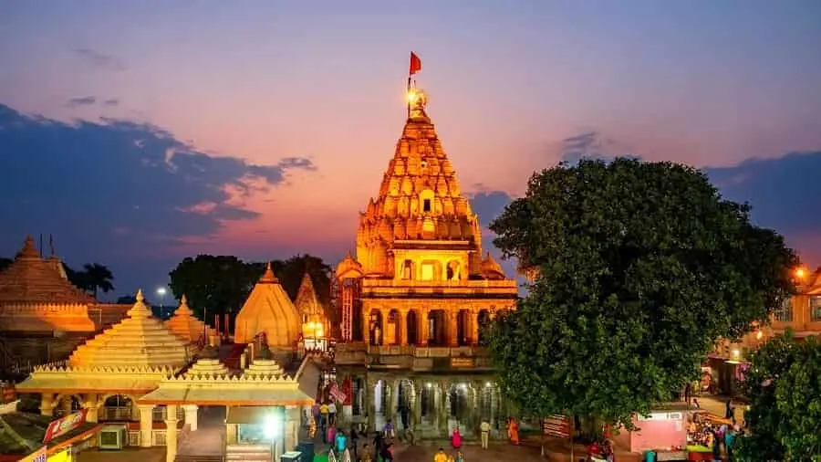 Evening view of Mahakaleshwar Jyotirlinga Temple in Ujjain, Madhya Pradesh, illuminated at sunset with devotees and temple complex in the foreground