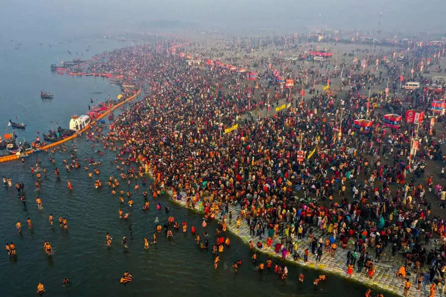 Aerial view of a massive crowd of devotees taking a holy dip at the confluence of rivers during the Kumbh Mela festival.