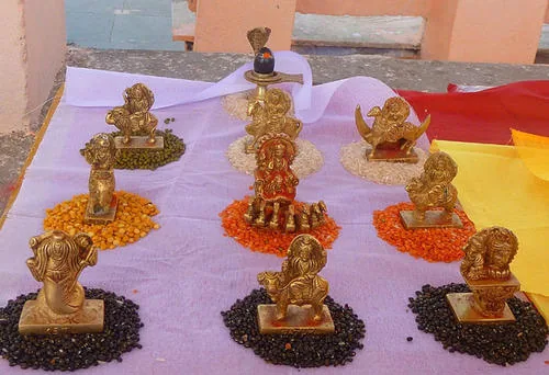 Navagraha idols placed on different lentils during a traditional Hindu ritual, representing the nine planetary deities for Navagraha Shanti Puja