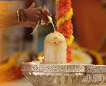 Devotee performing Rudrabhishek by pouring sacred water on a Shiva Lingam during a Hindu ritual, symbolizing devotion to Lord Shiva.